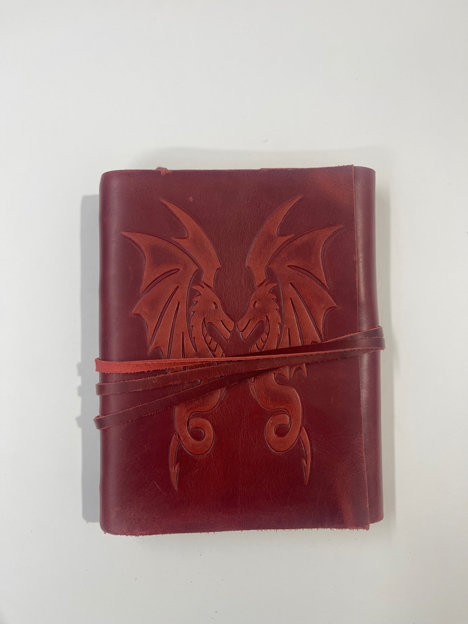 Libro de piel color rojo ocre con relieve de dragones